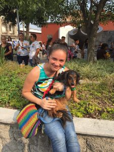 young woman holds dog while wearing rainbow gear